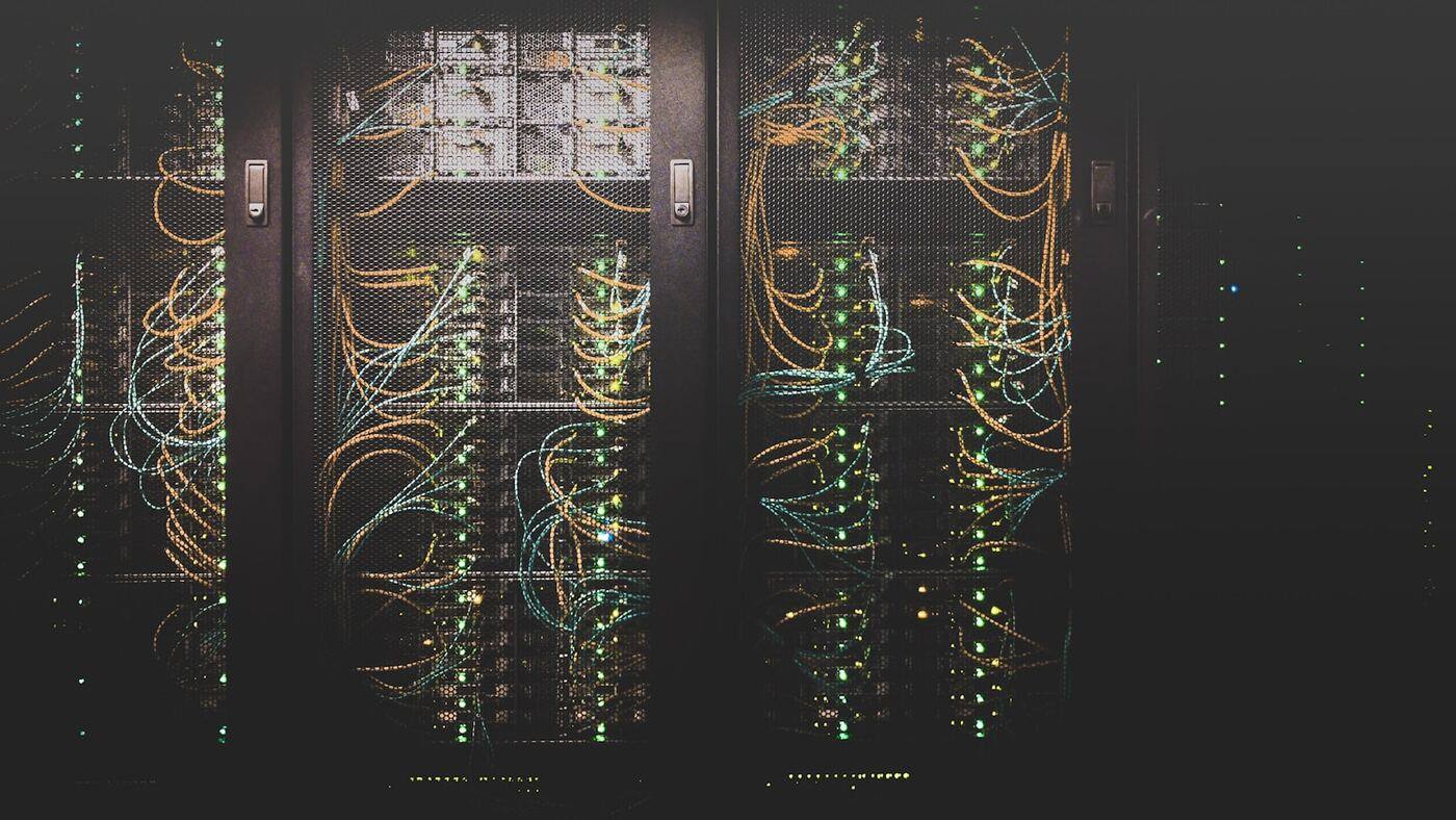 Row of illuminated server racks in a professional data center aisle with status lights and cable bundles