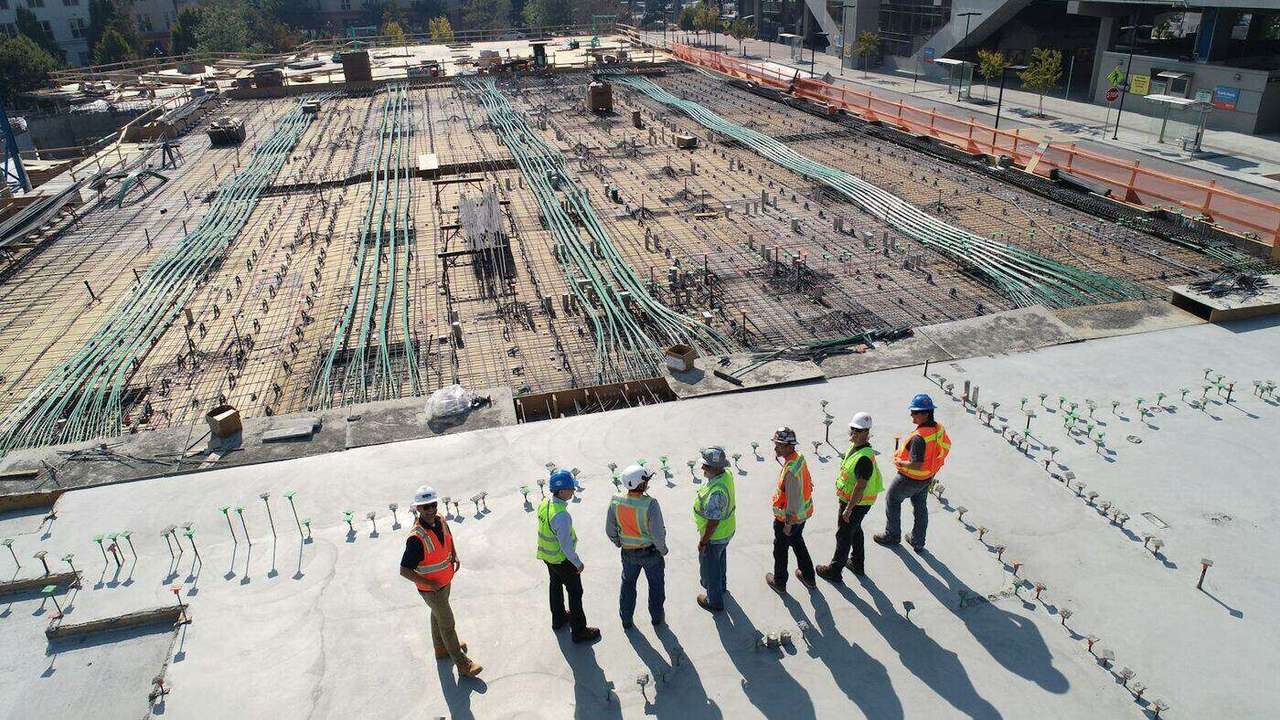 Construction workers in safety gear on an active building site representing coordinated technology and facilities project delivery